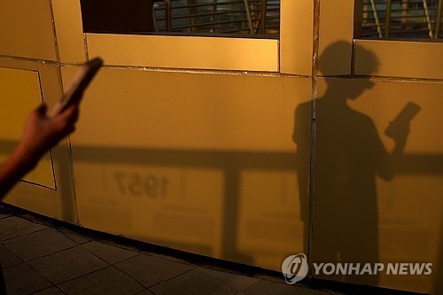 핸드폰을 보는 아동의 실루엣. 기사와 관련없는 자료사진입니다